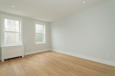 a living room with a wooden floor and two windows